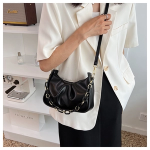 Detail of black pleated cloud bag featuring chunky acrylic chain and sleek faux leather texture