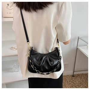 Detail of black pleated cloud bag with elegant acrylic chain and leather shoulder strap