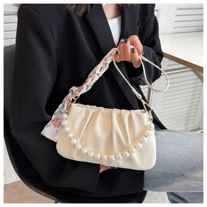Detail of cream white pleated bag with pearl chain and silk scarf handle on model
