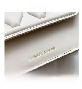 Close-up of cream leather bag featuring V-quilted stitching and gold embossed lettering
