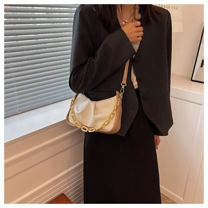 Close-up of beige ruched cloud bag with bold gold chain and leather strap details