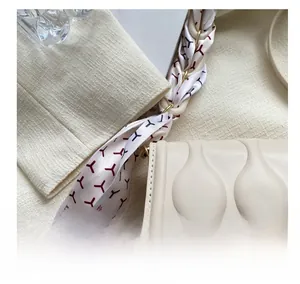 Detail of cream white embossed texture crossbody bag with decorative silk scarf accessory