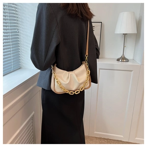 Detail of beige ruched cloud bag with glossy finish and gold chunky chain strap