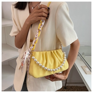 Detail of yellow pleated cloud bag featuring pearl strap and silk scarf handle accents