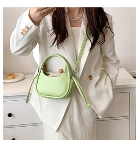 Détail d'un sac demi-lune vert clair avec pochette à cordon crème et bandoulière