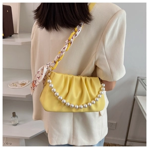 Detailed view of yellow pleated cloud bag with pearl strap and scarf chain handle