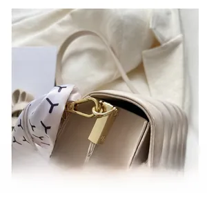 Detailed macro view of beige embossed small square bag with golden hook and printed scarf