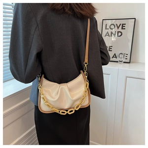 Chic cream pleated cloud bag with chunky gold chain detail shown on shoulder