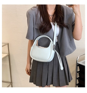 Sac à main bleu clair porté en bandoulière sur un tailleur gris pour femmes chic
