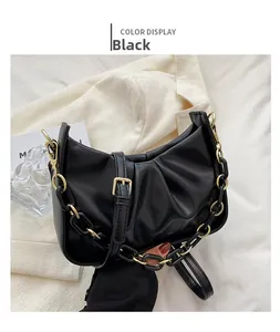 Detail of black pleated cloud bag featuring gold chain and adjustable leather strap