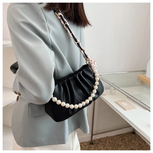 Detail of black pleated underarm bag featuring pearl chain and floral scarf strap
