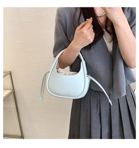 Détail d'un mini sac demi-lune bleu clair avec sac intérieur à cordon et longue sangle à glands