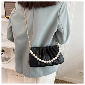 Detail view of black ruched cloud bag with large pearl chain and gold metal strap