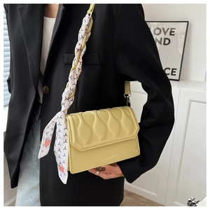 Detail of yellow embossed crossbody bag with silk scarf woven into the chain strap