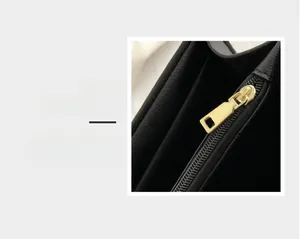 Detailed macro view of the smooth gold hardware zipper on this black leather shoulder bag