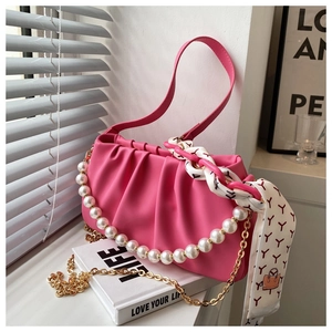 Detail of fuchsia pleated cloud bag with pearl strap, gold chain and silk scarf