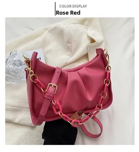 Detail of rose red ruched cloud bag featuring acrylic chain and adjustable strap