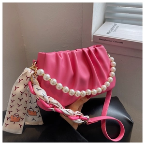 Close-up of rose pink pleated crossbody bag with pearl chain and silk scarf detail