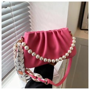 Close-up of pink pleated shoulder bag with pearl handle and patterned silk scarf