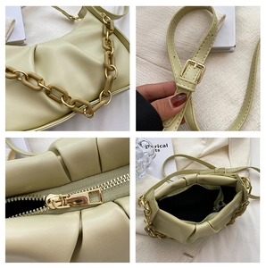 Detail view of light green pleated handbag showing the acrylic chain and metal zipper