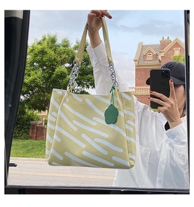 Mirror selfie showing a yellow and white wavy striped tote bag with green floral charm