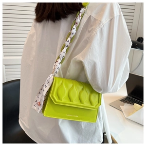 Detail of green leather bag with embossed texture and silk scarf wrapped chain strap