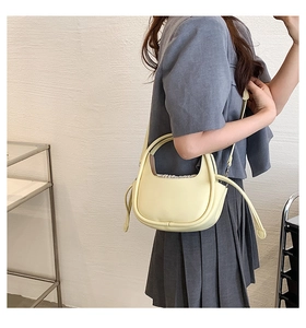 Vue détaillée du sac à main en cuir jaune crème avec fermeture à cordon et fine bandoulière