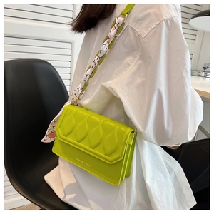 Detail of neon green crossbody bag with textured wave pattern and silk scarf strap