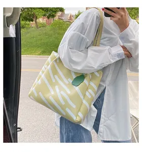 Detail of yellow tote bag with white patterns and a green leaf pendant on the strap