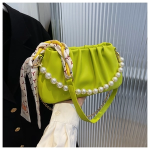 Detail of neon green pleated bag with pearl handle and printed silk scarf accessory