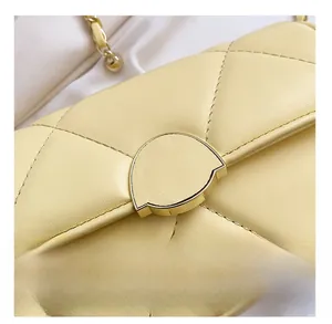 Détail de sac matelassé jaune avec boucle dorée semi-circulaire et bandoulière en chaîne