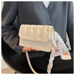 Detail of off-white quilted shoulder bag with chain strap and decorative silk scarf