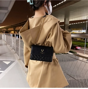 Detail of black quilted chain bag with gold deer hardware and leather texture