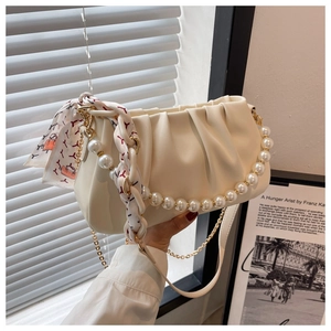Close-up of cream white pleated cloud bag with pearl handle and silk scarf detail