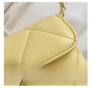 Détail d'un sac à main en cuir matelassé jaune avec coutures fines et chaîne dorée