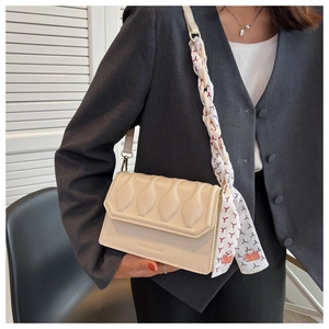 Detail of cream flap crossbody bag with wavy texture and silk scarf wrapped handle