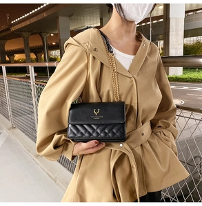 Close-up of black quilted shoulder bag with gold chain strap and metal deer emblem