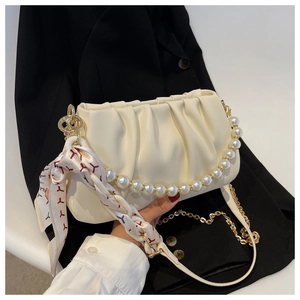 Detail of cream pleated crossbody bag with pearl handle and silk scarf accessory