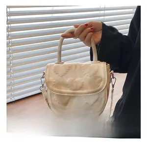 Détail de la surface en cuir PU blanc gaufré de cœurs et de la poignée arrondie du sac selle