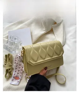 Detail of yellow embossed crossbody bag featuring wavy quilting and decorative silk scarf