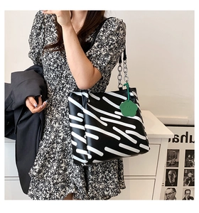 Detail of zebra pattern tote bag with silver chain strap and green floral charm