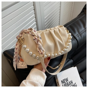 Close-up of creamy white ruched handbag with pearl handle and silk scarf detail