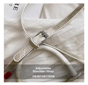 Détail de la bandoulière réglable en cuir avec boucle argentée sur le sac besace