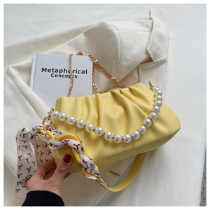 Detail of yellow pleated cloud bag with pearl handle, gold chain and printed silk scarf