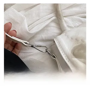 Gros plan du crochet métallique argenté sur le sac à bandoulière en cuir blanc texturé