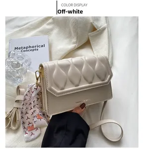Detail of cream white quilted crossbody bag with silk scarf and gold hardware accents
