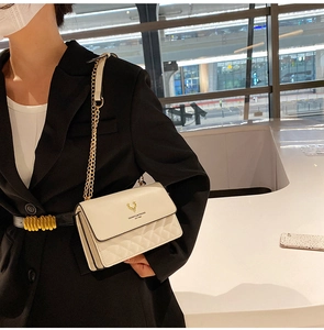 Detail of white quilted leather crossbody bag featuring gold deer logo and chain strap