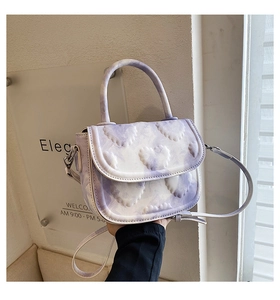Détail du sac selle à motif marbré lavande avec textures de cœur gaufrées et bandoulière