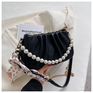 Detail of black pleated cloud bag with large pearl handle and silk scarf accessory