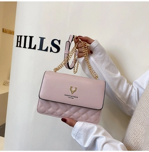 Detail of pink quilted crossbody bag with golden deer head logo and chain strap